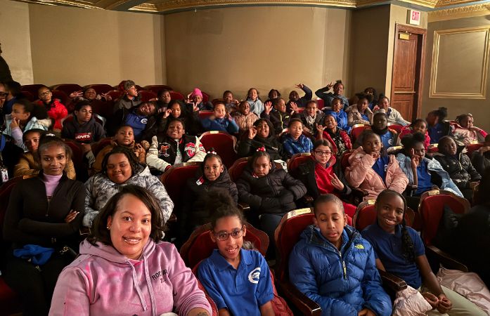  4th grade students sitting and waiting to watch Harlem Dance Company on stage at the opera house.
